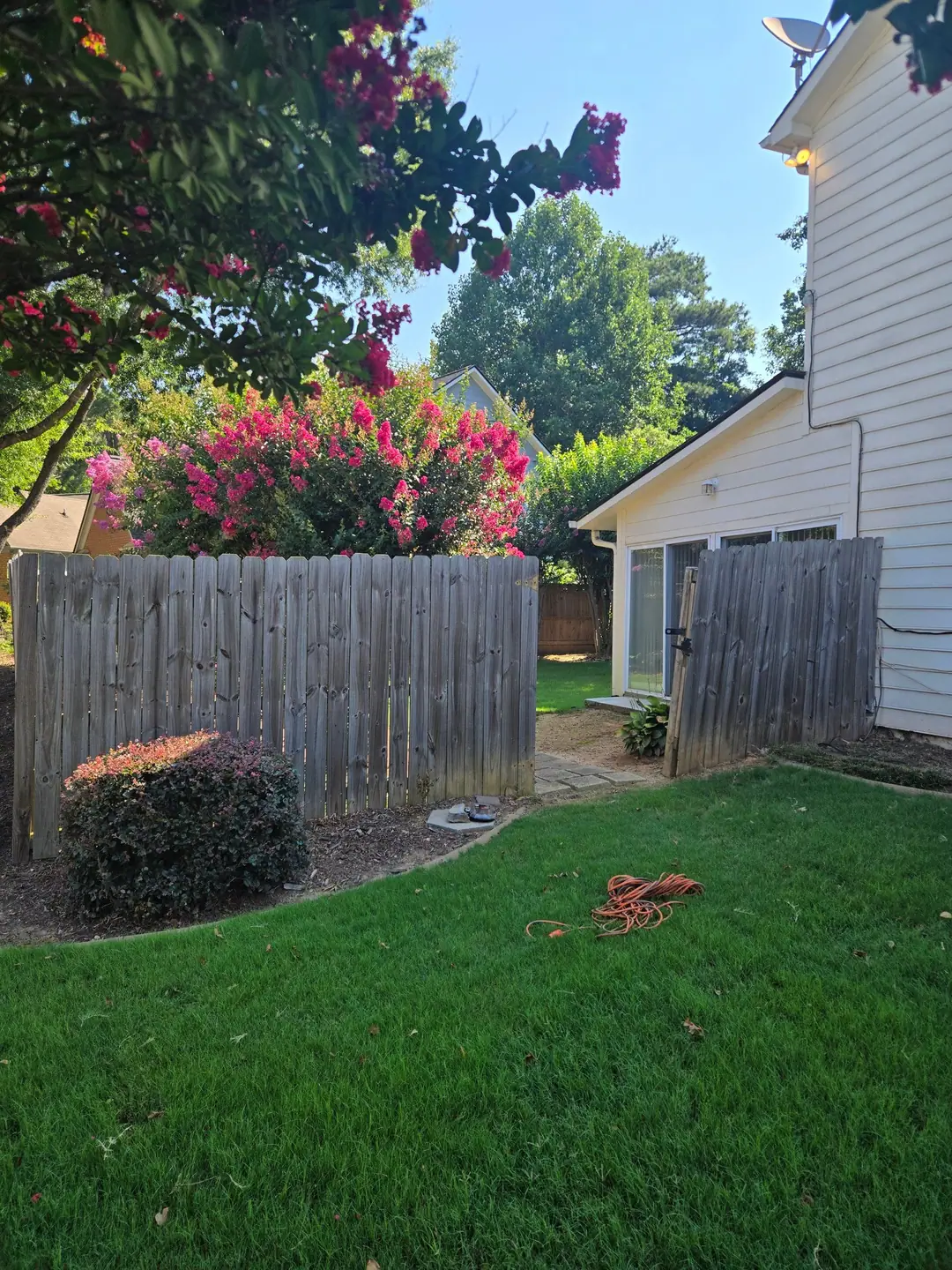 Before: an old gray wood fence and a sagging gate beside a house with blooming crepe myrtles